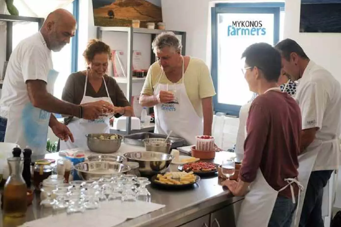 Enthusiastic travelers learning to cook traditional Mykonian dishes with a local chef
